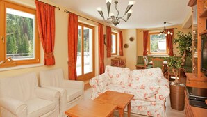Una sala acogedora con un sofá, sillas, una mesa de madera y un televisor.