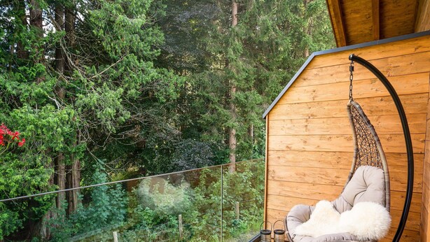 A wooden deck with a hanging chair and two lanterns. - Luxurious Holiday Home With Sauna (Krimml)