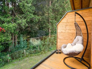 A wooden deck with a hanging chair and two lanterns. - Luxurious Holiday Home With Sauna (Krimml)