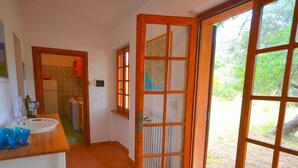 Una cocina con mostrador de madera, un lavamanos y un ventanal con vistas al verdor.