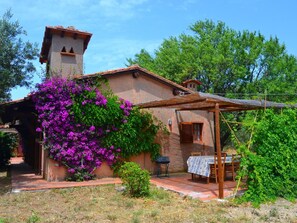 Une maison de campagne au cachet rustique, avec une façade en pierre, une pergola en bois et une table dressée pour le repas.