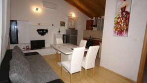 Un espace de vie compact comprenant un canapé, une table à manger, des chaises, un coin cuisine et un tableau accroché au mur.