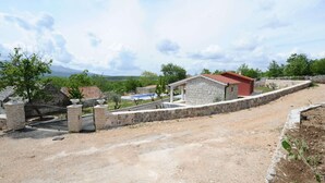 Une propriété rurale dotée d’un mur en pierre, d’un petit bâtiment avec un toit rouge et d’une allée pavée.