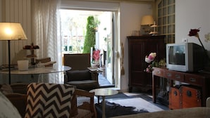 A living room with a sofa, chairs, a coffee table, a TV, and a cabinet.