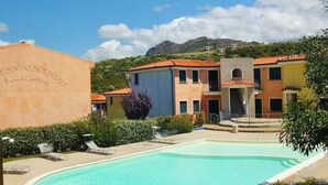 Piscina rodeada por edifícios, com montanhas ao fundo.