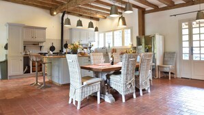 A spacious kitchen with a dining area, wooden beams, and a large window. - Luxury Villa in Dordogne With Pool & Privacy (Port-Sainte-Foy-et-Ponchapt)