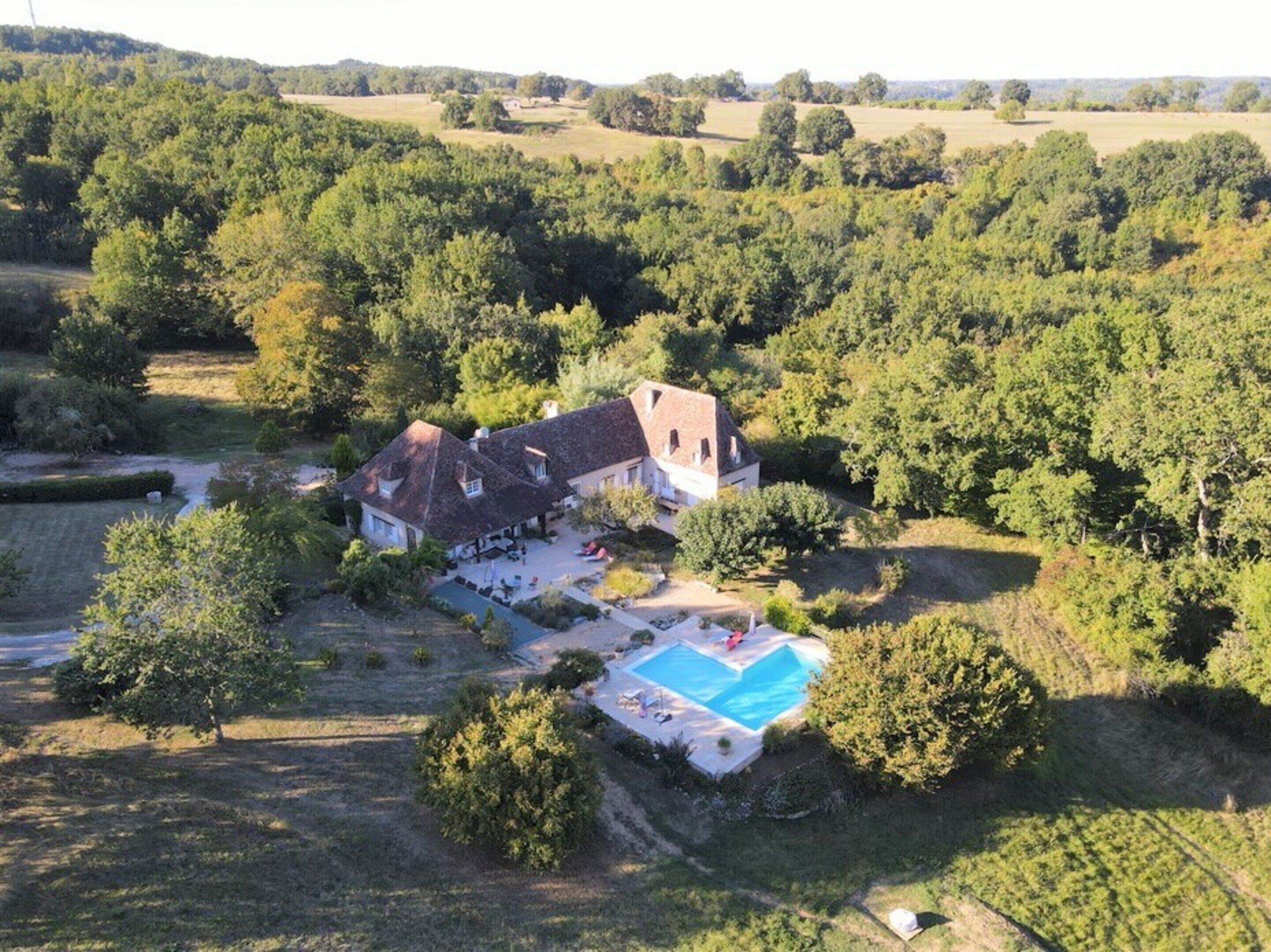 Una casa rodeada de árboles, con piscina.
