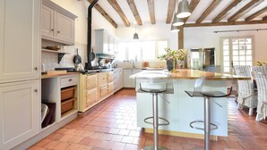 A kitchen with white cabinets, a wooden ceiling, and a bar area with stools. - Luxury Villa in Dordogne With Pool & Privacy (Port-Sainte-Foy-et-Ponchapt)