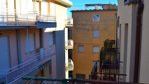 Un edificio residenziale a più piani con balconi, un’area lavanderia ben visibile e un cielo sereno.