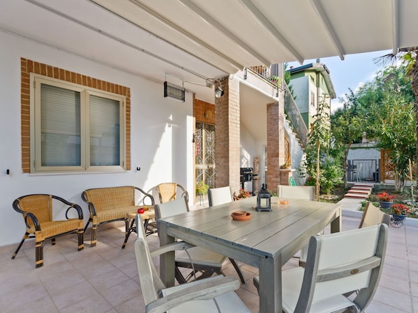 An outdoor patio with a table and chairs, a brick wall, and a covered area with a railing. - Spacious Apartment near Saludecio (Saludecio)