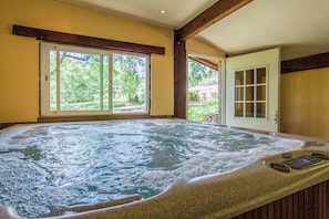 A hot tub with a view of a garden through a sliding door.