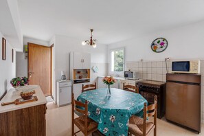 A compact kitchen with a dining table, chairs, a refrigerator, a microwave, and a sink. - Priziac Garden Hideaway (Priziac)
