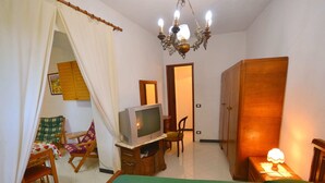 A bedroom with a bed, a television, a chair, a wardrobe, and a chandelier. - Apartment in Rio Near Roman Bridge (Sesta Godano)