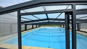 A covered swimming pool with a glass enclosure, a clear blue pool, and a 'SECURITY' sign. - Spacious Holiday Home With Private Pool (Uzech)
