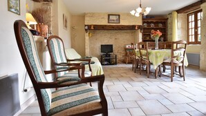 A room with a fireplace, a television, a dining table with chairs, and a large window. - Spacious Holiday Home With Private Pool (Uzech)