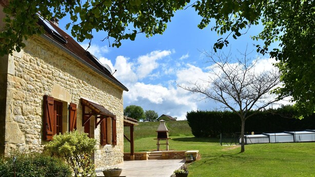 A stone building with a patio, a barbecue grill, and a grassy yard. - Spacious Holiday Home With Private Pool (Uzech)