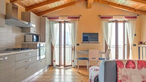 A compact kitchen with modern appliances, a dining area with a table and chairs, and a cozy sleeping area with a bed. - Belvilla by OYO Romantica (Gravedona)