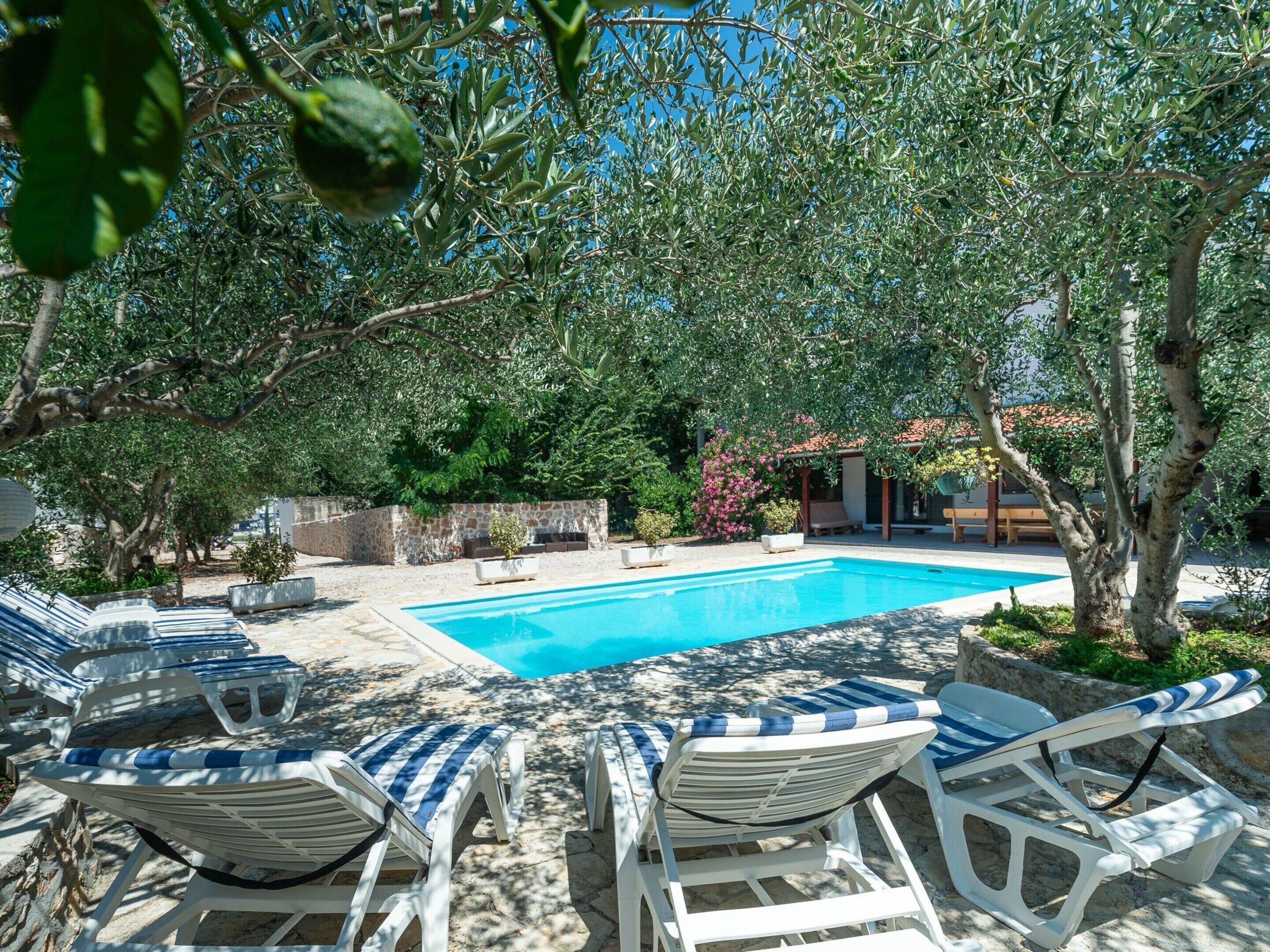 A pool area with lounge chairs and a stone wall.
