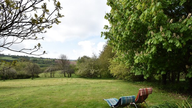 A grassy outdoor area with a single lounge chair and a blanket. - Normandy Bakery Retreat (Torigny-les-Villes)