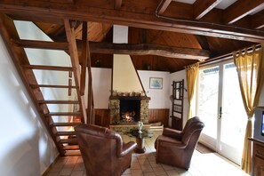 A cozy room with a fireplace, wooden beams, a staircase, and leather chairs. - Normandy Bakery Retreat (Torigny-les-Villes)