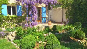 A garden with purple flowering vines, a blue door, and a stone pathway. - Verdon Views: Pool & Terrace (Montagnac-Montpezat)