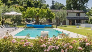 A pool area with lounge chairs, a blue boat, and a stone building in the background. - Scenic Villa With Heated Pool (Sant'Ippolito)