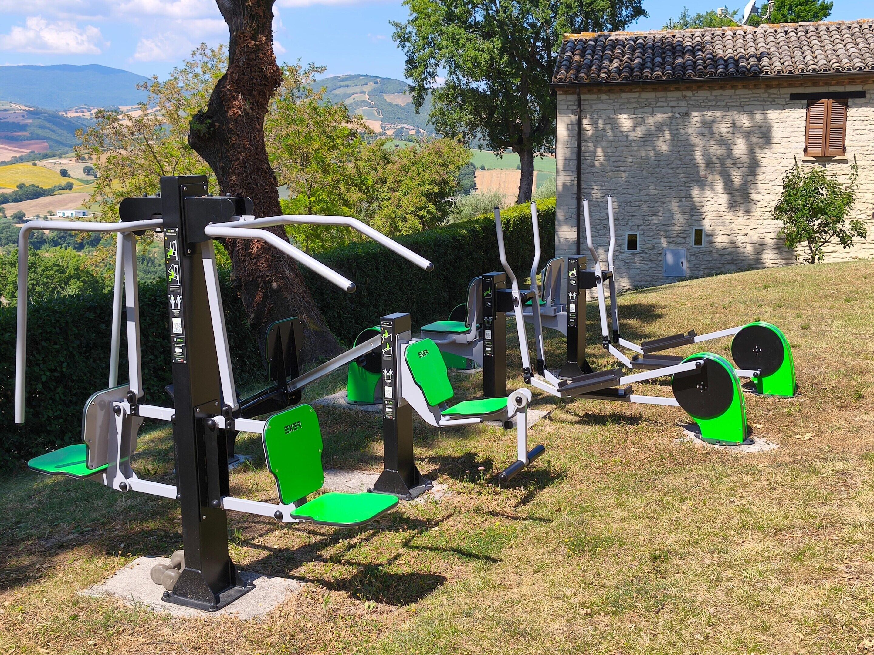 Outdoor exercise equipment in a park with a stone building in the background.