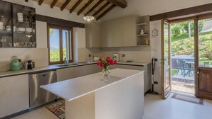 A modern kitchen with a large island, stainless steel appliances, and a view of the outdoors. - Scenic Villa With Heated Pool (Sant'Ippolito)