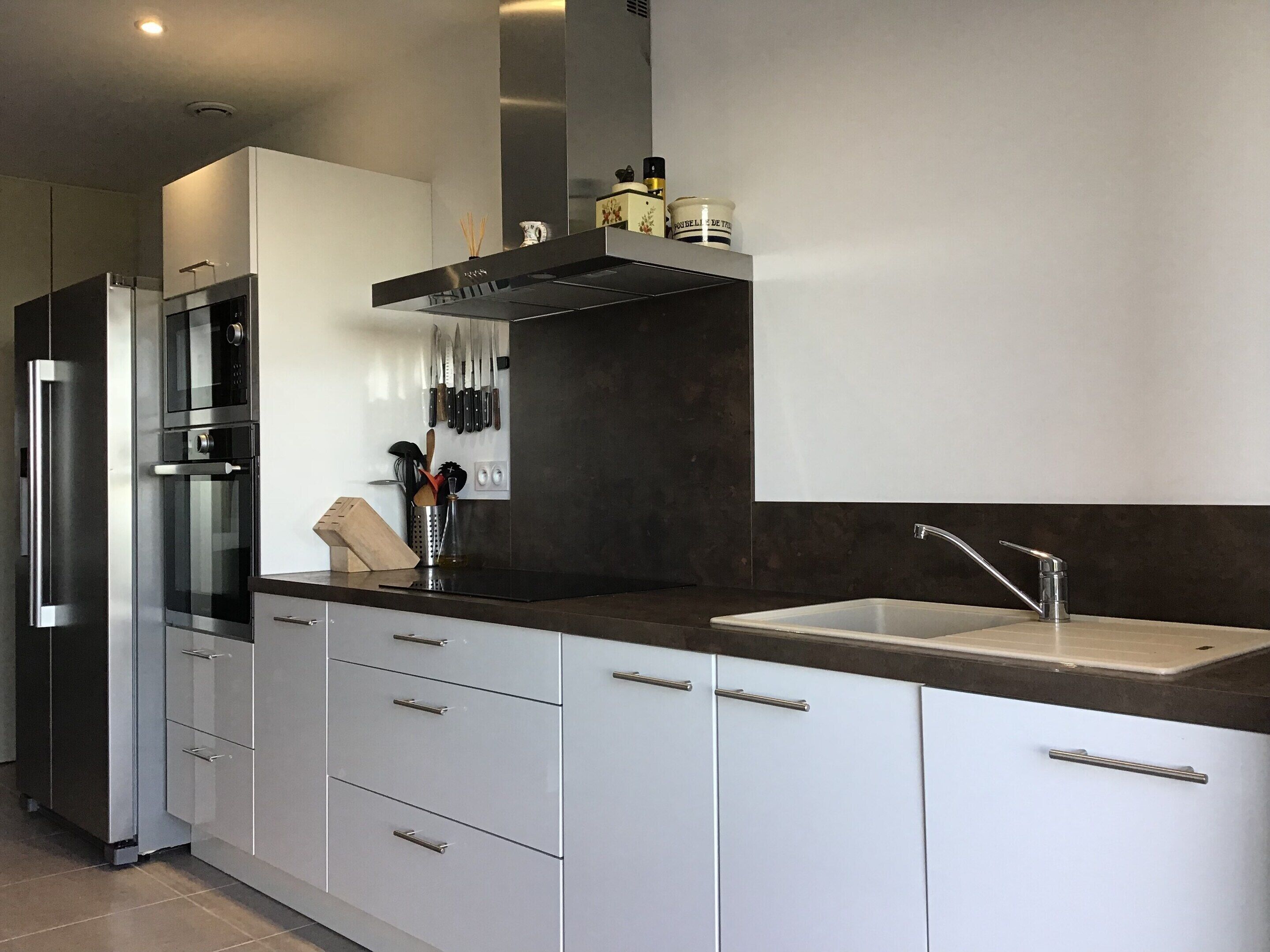 Una cocina moderna con armarios blancos, electrodomésticos de acero inoxidable y encimera oscura.