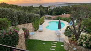 A backyard with a swimming pool, lounge chairs, and a view of the sea. - Mediterranean Villa of Liscia di Vacca (Arzachena)