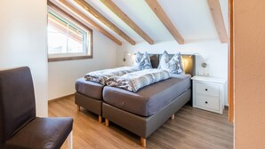 A bedroom with a bed, bedside tables, a chair, and a window.