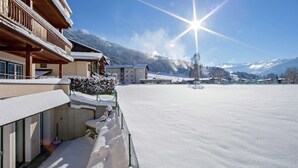 A snow-covered outdoor area with a wooden building, a clear sky, and mountains in the background.