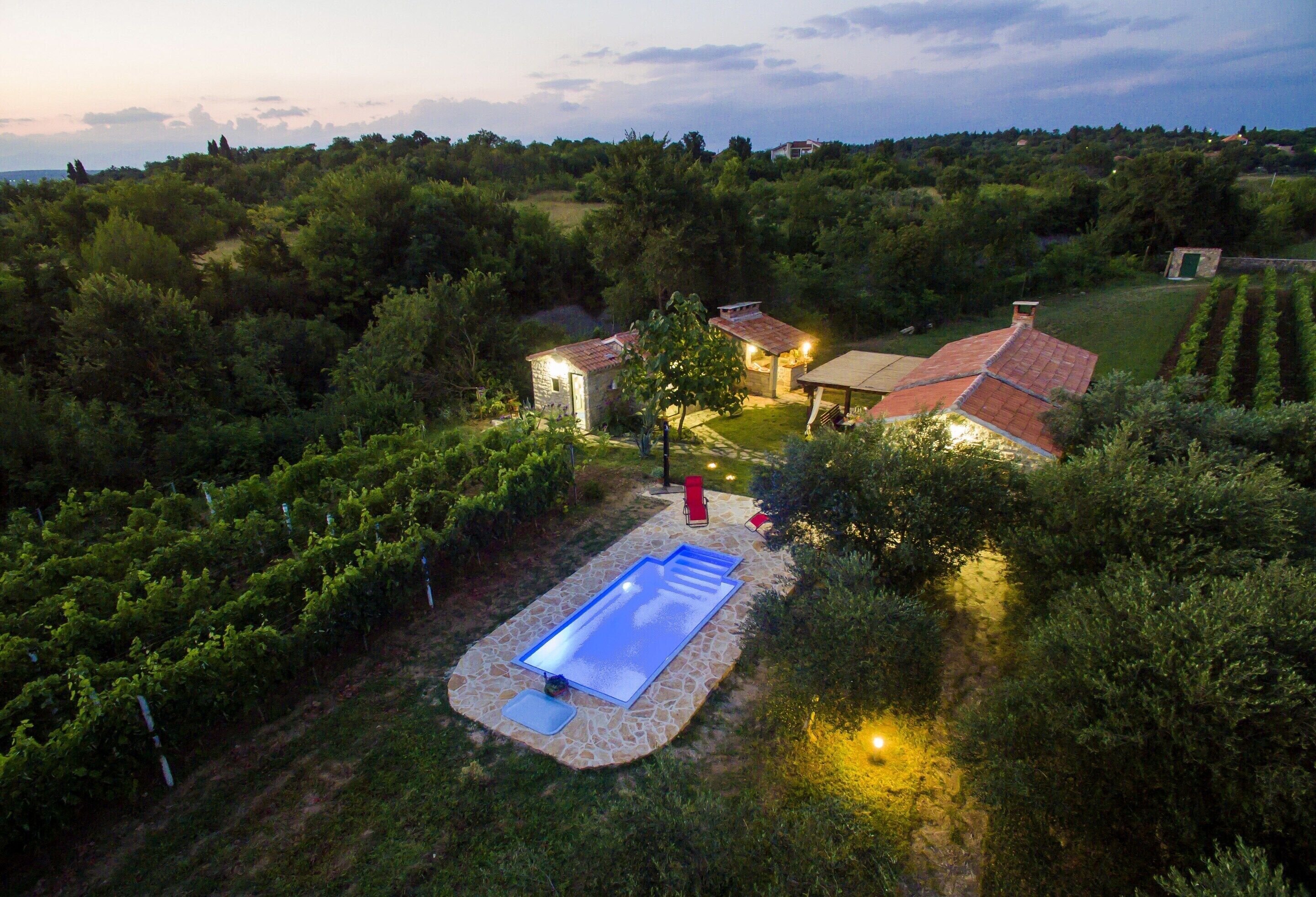 Un vigneto con piscina, vialetti in pietra e un gazebo.