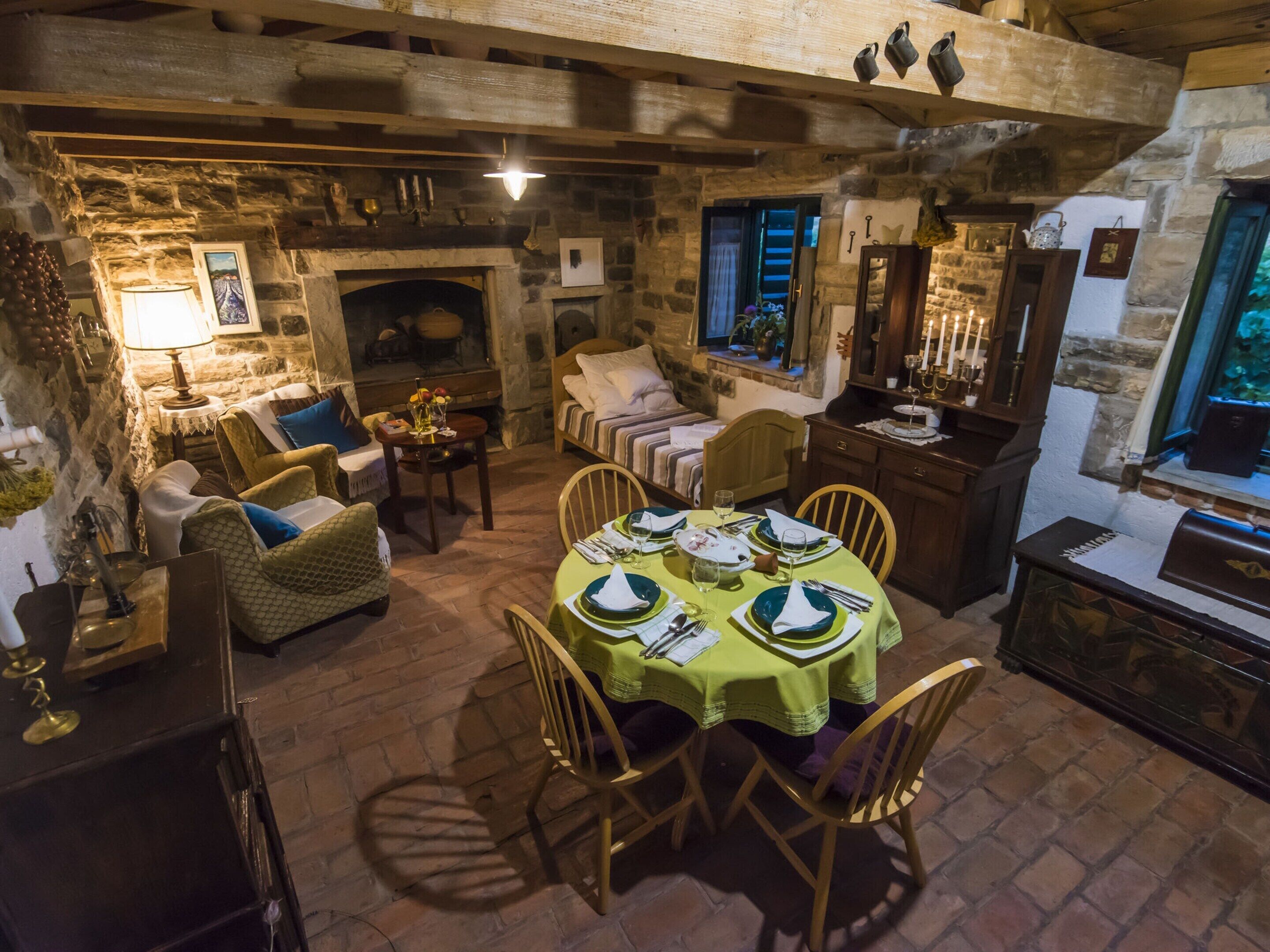 Una sala da pranzo rustica con camino in pietra, arredi in legno e una tavola apparecchiata per un pasto.
