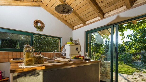 A kitchen with a wooden ceiling, a large window, and a view of a garden. - Holiday Home Near Adriatic Sea and Krka Falls (Benkovac)