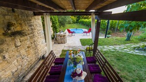 A covered patio with a stone wall, a pool, and outdoor seating. - Holiday Home Near Adriatic Sea and Krka Falls (Benkovac)