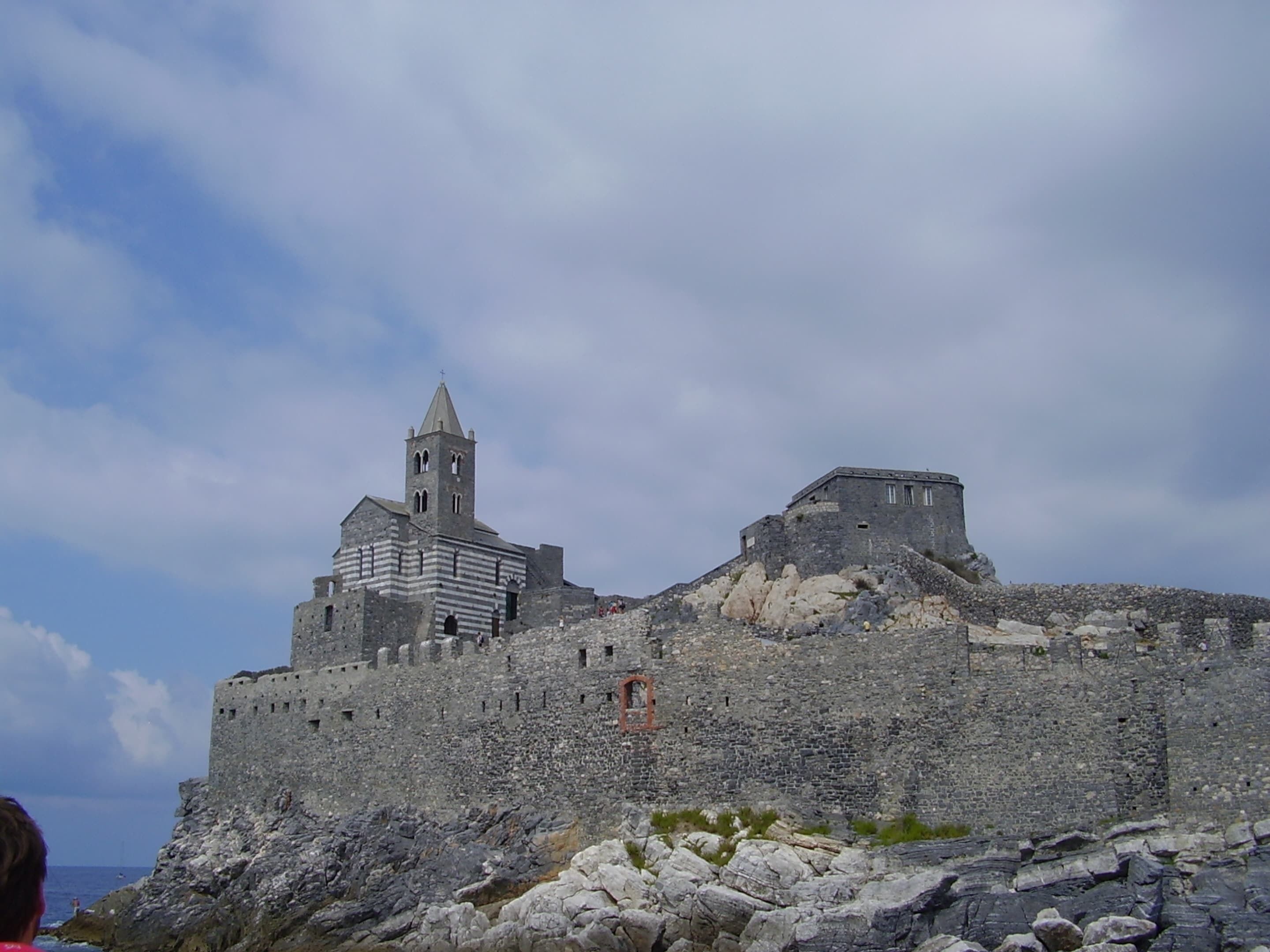 A historic stone fortress with a prominent tower and fortified walls, overlooking a rocky coastline.