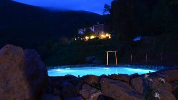 A swimming pool surrounded by rocks, with a house in the background.
