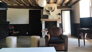 A rustic interior with exposed wooden beams, a fireplace with a bull skull decoration, a leather armchair, and a television. - Holiday Home in Angers With Private Garden (Bierné-les-Villages)