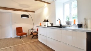 A modern kitchen with white cabinets, a wooden ceiling, a black pendant light, and a window with a view. - Holiday Home in Angers With Private Garden (Bierné-les-Villages)