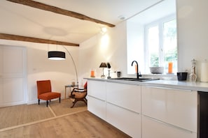 A modern kitchen with white cabinets, a wooden ceiling, a black pendant light, and a window with a view. - Holiday Home in Angers With Private Garden (Bierné-les-Villages)