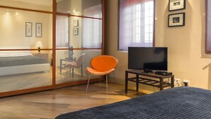 A modern hotel room with a large bed, a TV, a chair, and a window with blinds. - Farmhouse in Vinci With Pool and Tuscan Views (Vinci)