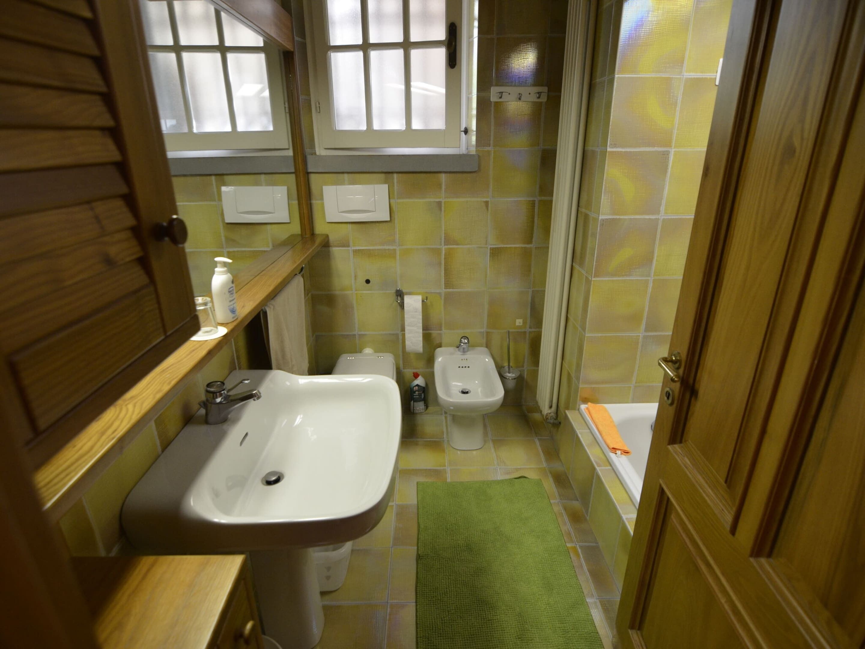 A small bathroom with a sink, bidet, and bathtub.