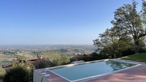 Une piscine offrant une vue sur une vallée et des bâtiments éloignés.