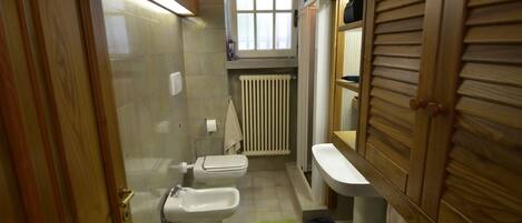 A compact bathroom with a toilet, bidet, and sink.