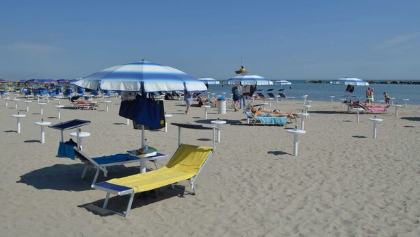 A beach with rows of sun loungers and umbrellas, some occupied, others empty. - Apartment in Gatteo Mare Near Beach (Gatteo)