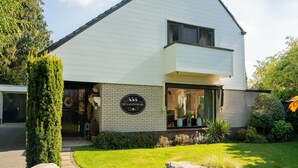 A modern two-story house with a prominent sign reading "DE GANZENMARS" on the front.