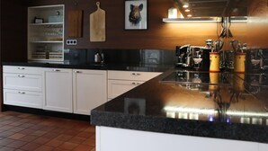 A modern kitchen with white cabinets, a black countertop, and a stainless steel range hood.