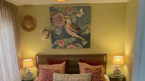 A neatly made bed with two pillows, a decorative painting above, and two bedside lamps.