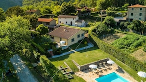 Une villa située sur une colline, dotée d’une piscine, de jardins aménagés en terrasses et d’un sentier en pierre.